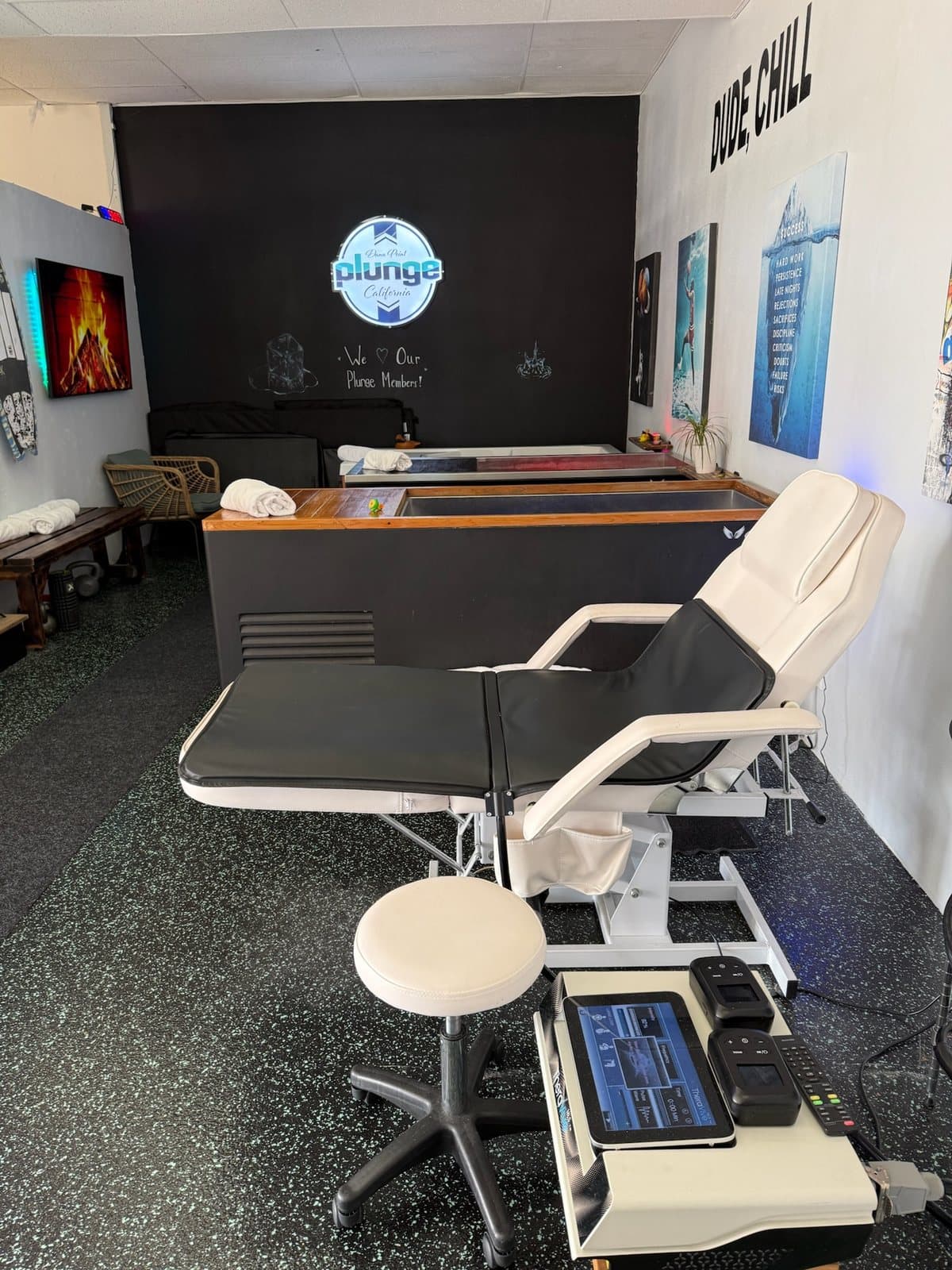 A treatment room with a therapy table, equipment cart and wall art