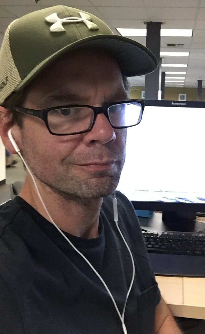 Rob Stickler at a contact-center workstation wearing earbuds, monitor and keyboard in front of him